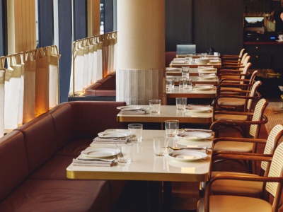 Elegant restaurant interior with neatly arranged tables and chairs, set with plates and glasses. Soft lighting and a serene, inviting ambiance are present.